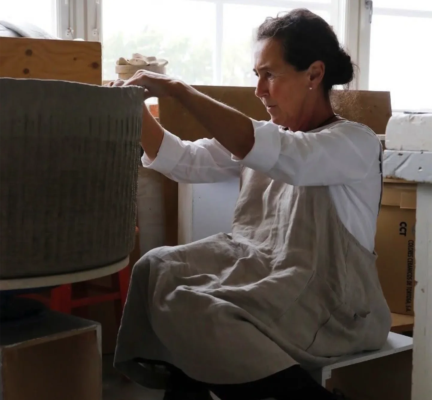 Hands shaping a large clay vessel in the studio